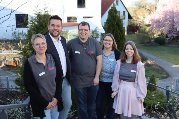 5 Personen lächeln in die Kamera