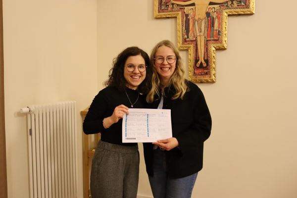 2 Personen posieren mit einer Unterschriftenliste und lächeln