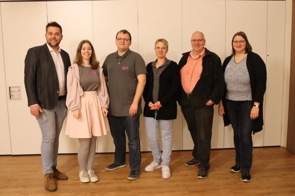 6 Personen stehen und lächeln in die Kamera