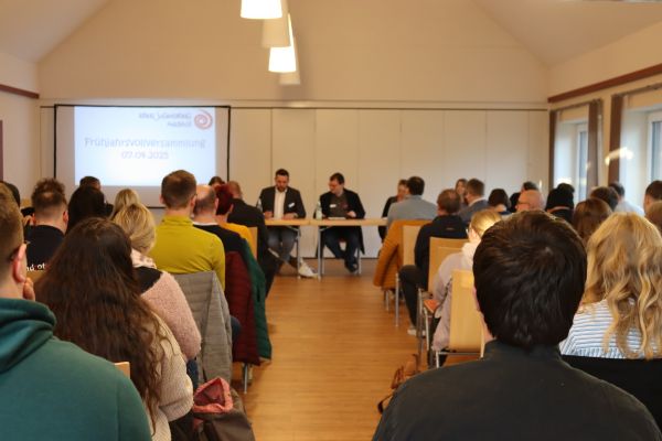 6 Personen sitzen halten einen Vortrag für 40 Personen