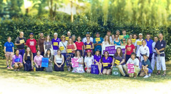 34 Personen stehen und knien mit Banner zum Tag der offenen Gesellschaft