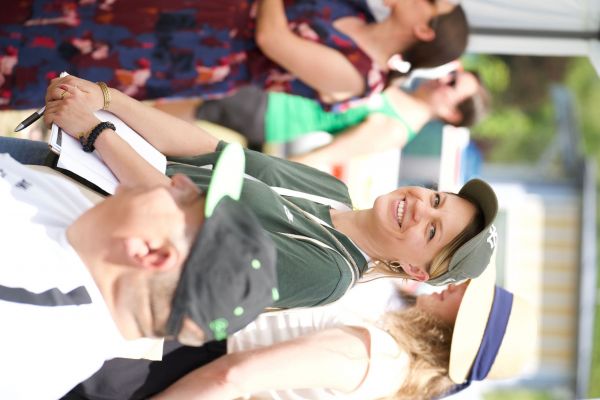 Organisatorin lächelt in die Kamera, umgeben von 4 Menschen