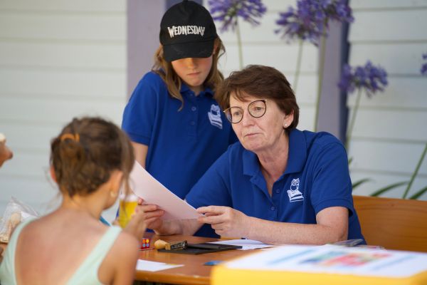 Ein Kind besucht den Infostand mit zwei Mitarbeiterinnen der Stadtbibliothek Herrieden