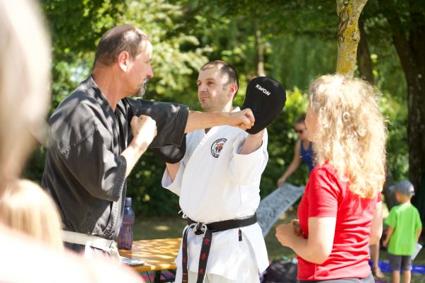 2 Männer führen den Zuschauenden einen Beispielsschlag aus dem Kampfsport vor