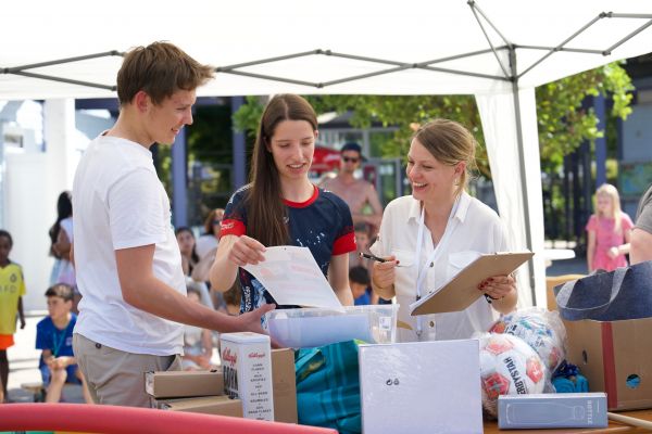 3 Personen organisierend lachend die Gewinnspielausteilung