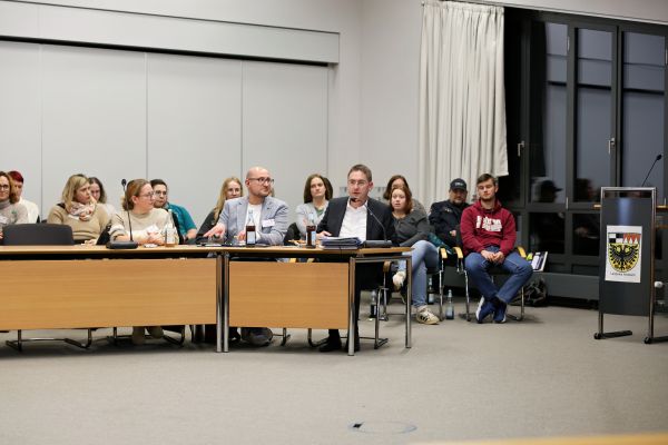 15 Personen sitzen in einem Besprechungsraum