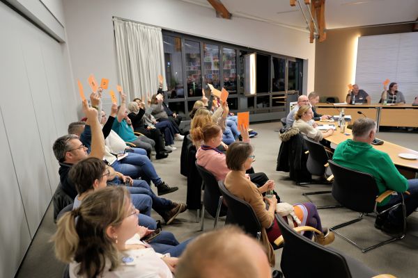 circa 30 Delegierte halten Stimmgarten nach oben, blick nach vorne