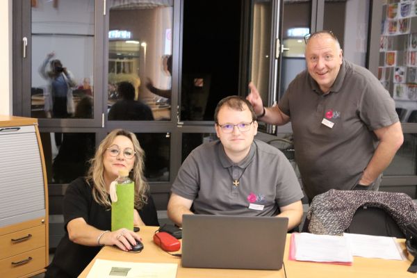 3 Personen arbeiten an einem Labtop und schauen in die Kamera