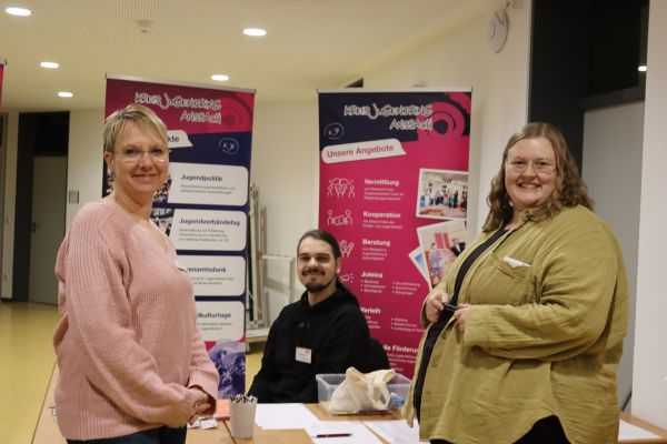 3 Personen vor dem KJR roll-up lächeln in die Kamera
