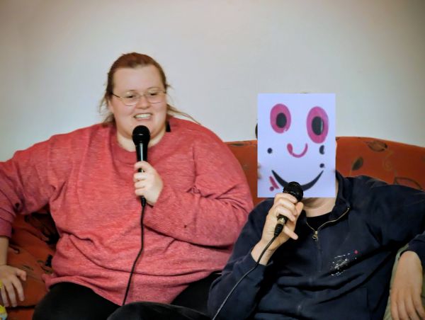 2 Personen singen beim Karaokeabend, einer trägt JUKUTA Maske