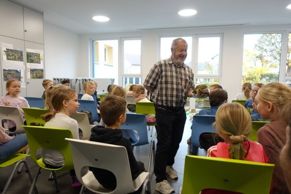 Mann präsentiert Riesenschnecken vor 1 Schulklasse