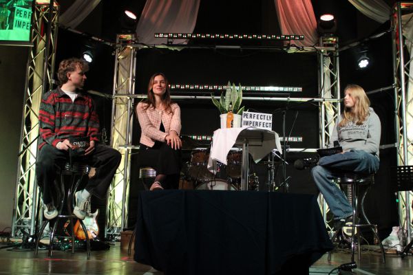 3 Personen sitzen bei Unterhaltung auf der Bühne