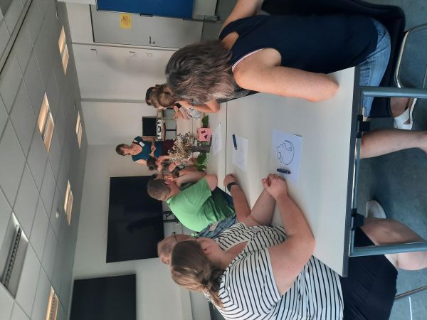 10 Seminarteilnehmer am Tisch lauchen der Dozentin