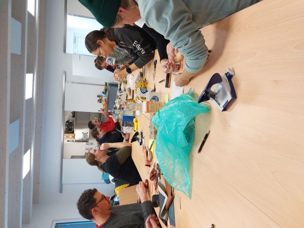 Menschen sitzen an einem Tisch & basteln mit Naturmaterilien