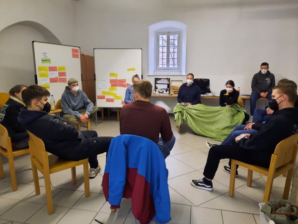 Eine Menschengruppe sitzt im stuhlkreis